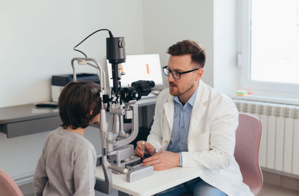 An optometrist conducting an eye exam for a young boy using a slit lamp.