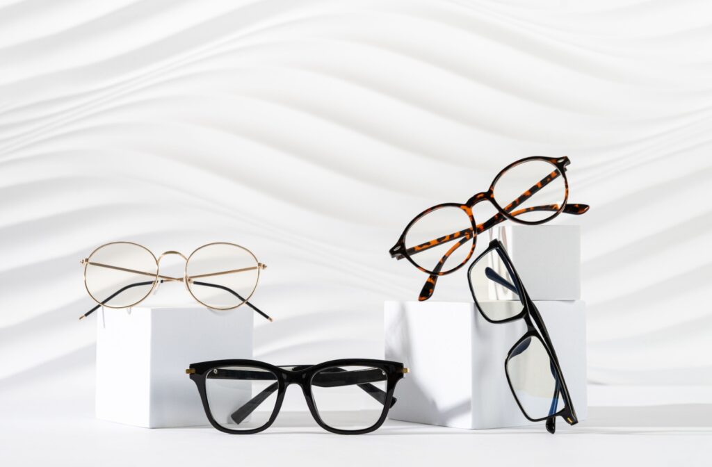 Various eyeglass frames from an optometrist's office on white blocks and in front of a white background.