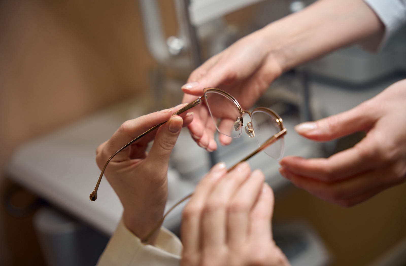 A close-up of an optometrist handing a pair of glasses to their patient after helping them choose the right frame and lenses for their needs.