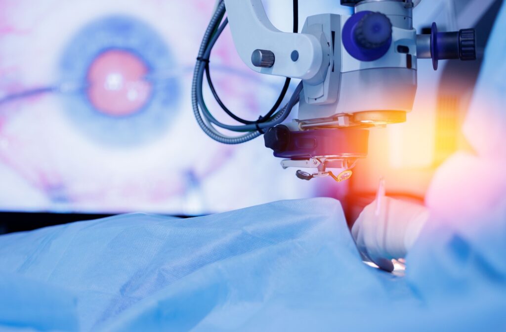 A patient covered by a blue sheet undergoing laser eye surgery, a close-up view of their eye on the screen behind them