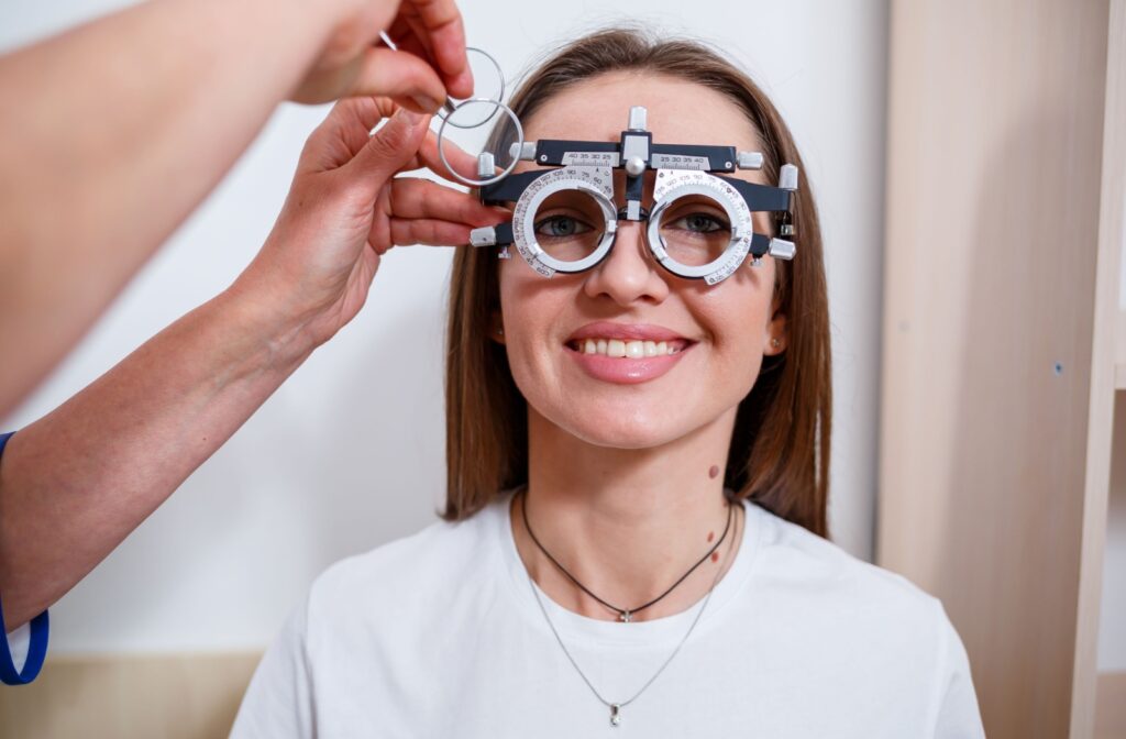 An optometrist uses trial lenses to measure their client for glasses while their client stares straight ahead.