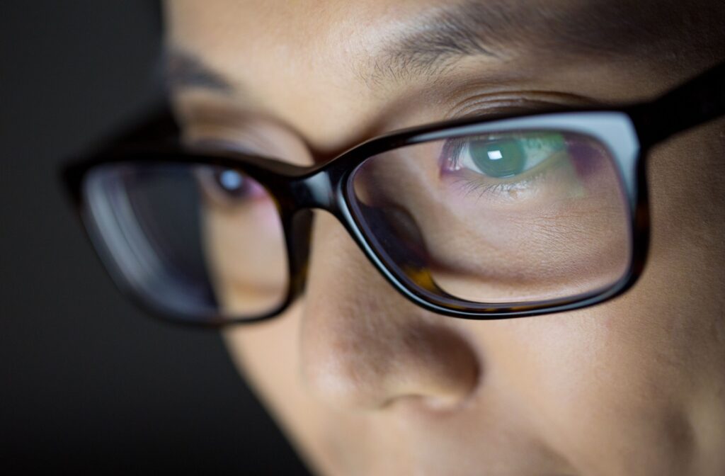 A close up of someone wearing glasses with a digital screen reflecting in the glasses